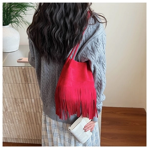 Detail of red suede shoulder bag with long fringes and soft retro texture finish