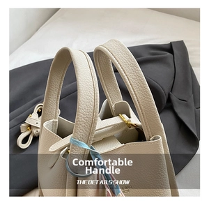 Beige leather bucket bag handle detail showing premium pebbled texture and metal hardware.