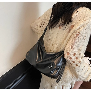 Detail of soft black faux leather tote bag with silver ring accent on a shoulder