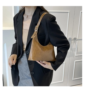 Brown vintage glossy leather baguette bag with crescent shape and silver buckle detail