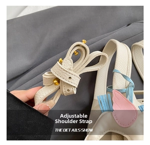 Detail view of women bucket bag shoulder strap with wing pendant, premium leather and hardware.