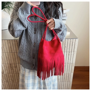 Detalle de bolso de cubo rojo con flecos y textura mate con asa trenzada