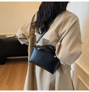 Detail der schwarzen matten Leder-Schultertasche mit silbernen Nieten getragen am Modell