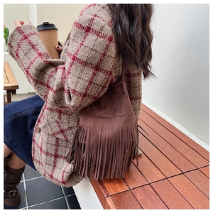 Detail of dark brown suede shoulder bag with long fringes and leather strap