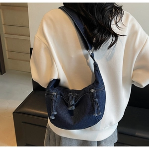 Detailed view of dark blue denim half-moon crossbody bag shown on model for size and style