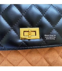 Macro shot of black quilted leather stitching and gold rectangular metal twist lock detail