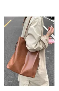 Detail view of large brown oil-wax leather tote bag with wide straps worn on shoulder
