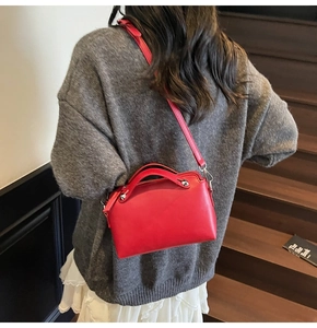 Detailansicht einer roten Ledertasche mit Silbernieten und einem Crossbody-Gurt