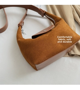 Détail du sac à main marron en daim avec surpiqûres en cuir et fermeture éclair en métal