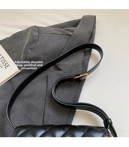 Detailed shot of black quilted bag with adjustable shoulder strap and gold hardware
