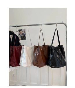 Row of large tote bags in burgundy, white, brown and black hanging on a metal rack