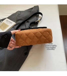 Macro detail of brown quilted suede shoulder bag with gold buckle and black strap