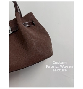 Macro detail of dark brown woven texture with matte suede finish and metal buckle