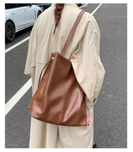 Detailed view of a brown vintage leather tote bag with drawstring closure on model