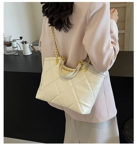 Detail of quilted leather tote bag in cream with golden chain strap on model
