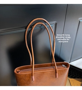 Close-up of smooth long leather straps and metallic zipper on brown vintage bucket bag