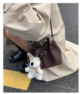 Dark brown pleated bucket bag detail shot showcasing unique texture, strap and cute bear charm.