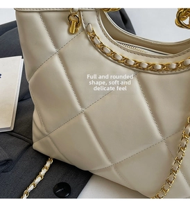 Detailed close-up of cream white quilted tote bag with golden metal chain strap
