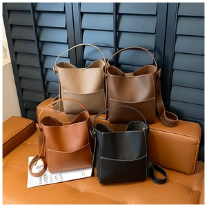 Detailed display of bucket bags in beige, brown, and black with adjustable straps