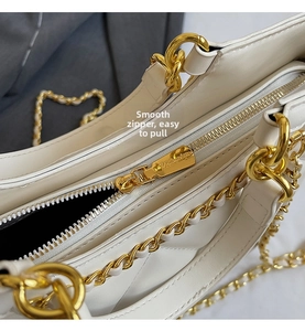 Detail of smooth gold zipper and chain strap on white quilted faux leather tote bag