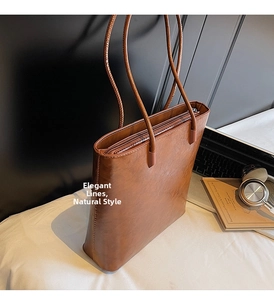 Detail view of deep brown faux leather tote bag with long shoulder straps and zipper closure