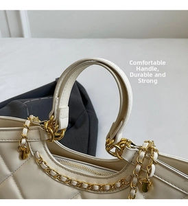 Detail of white quilted tote bag featuring golden chain and reinforced round handle