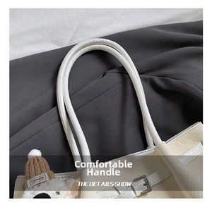 Détail du sac cabas tissé crème avec anse en cuir lisse et breloque ours en peluche