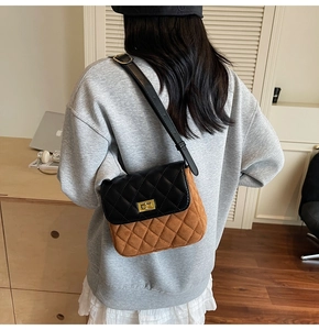 Detail view of a brown and black quilted crossbody bag with a golden metal twist lock