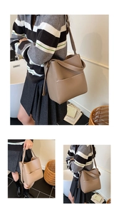 Detail of brown leather bucket bag with white contrast stitching and versatile wide strap