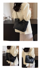 Detail of black quilted tote bag with elegant gold chain strap on office attire