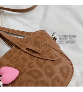 Detail of leopard print suede texture with a pink heart charm on a brown shoulder bag