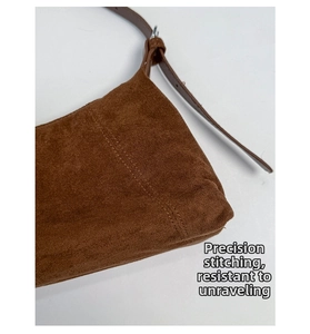 Detailed macro view of the brown suede bag showing precise stitching and silver buckle