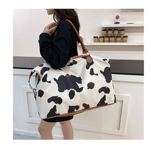 Large capacity leopard print travel bag with brown leather trim carried by a model