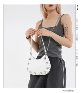 Detail of white moon bag featuring metallic studs and a mixed chain leather strap