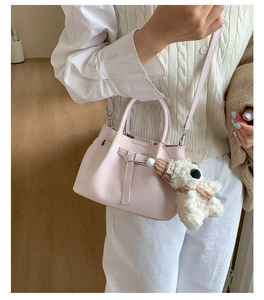 Close-up detail of stylish pink PU leather shoulder bag with chic belt buckle and cute bear charm.
