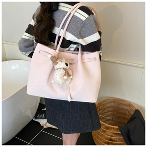 Détail du sac fourre-tout en cuir rose clair avec boucle et charmant ours en peluche blanc