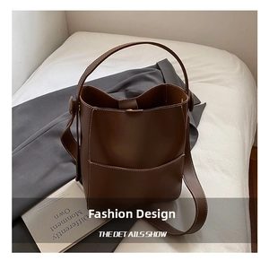 Detail view of dark brown leather bucket bag showing white contrast stitching and texture