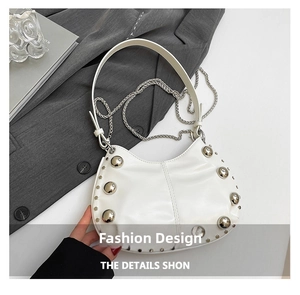 Close-up of white leather crescent bag with silver stud rivets and chain detail