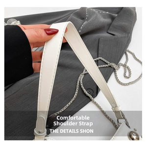 Detail of white leather shoulder strap with silver chain and fine stitching on handbags
