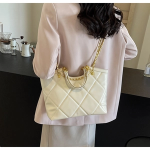 Quilted tote bag in cream white shown on a model's shoulder for size perspective