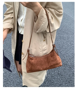 Detailed view of brown matte suede texture and vertical stitching on large crossbody bag
