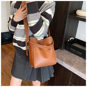 Detail of brown leather bucket bag with white contrast stitching and metal ring buckle