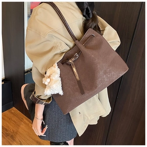 Détail d'un cabas en cuir marron avec boucle métallique et charmant mouton en peluche blanc