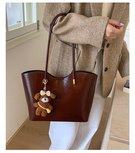 Détail d'un cabas marron foncé verni avec un joli pendentif ours en peluche