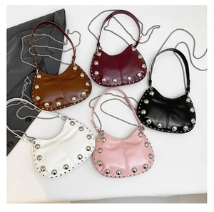 Flat lay of leather crescent bags in five colors featuring large silver studs and chain straps