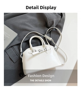 Detail view of white leather crescent handbag with silver metal eyelets on grey blazer