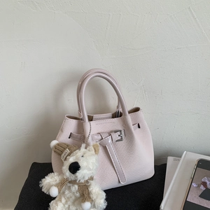Close-up of pink woven tote bag with leather buckle and cute brown teddy bear charm
