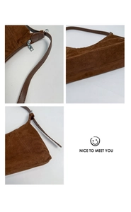 Detail of brown suede handbag featuring silver zipper and neat decorative double stitching