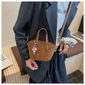Close-up of brown leopard print crossbody bag with pink heart pendant in a lifestyle setting