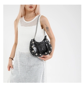 Close-up of black crescent bag with silver rivet studs and stylish metal chain strap